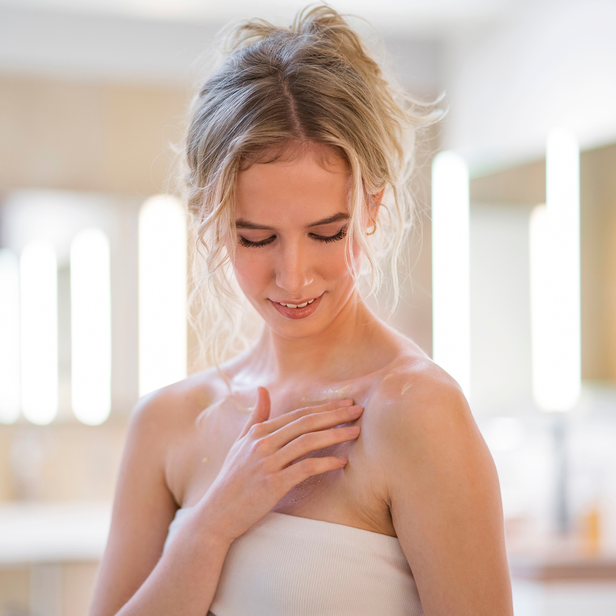 Frau trägt eine tägliche Pflege auf ihr Dekolletee auf