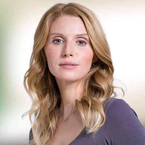 Frau mit blonden, langen Haaren vor grün-braunem Hintergrund