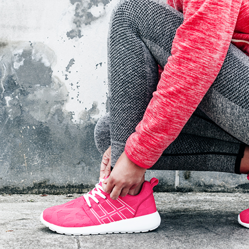 Frau schnürt ihre Sportschuhe