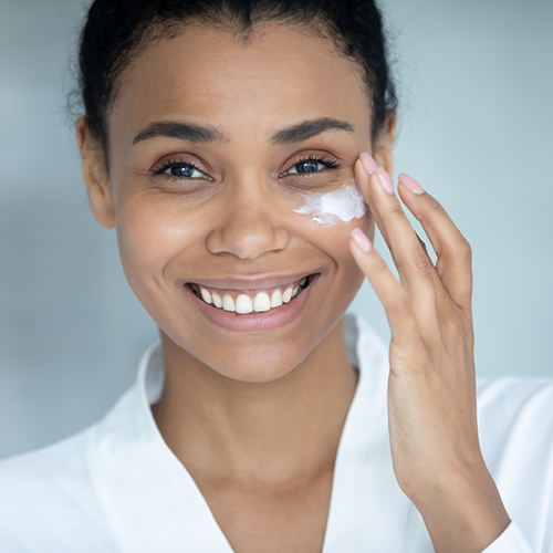 Lächelnde Frau verwendet Anti-Aging-Creme im Gesicht