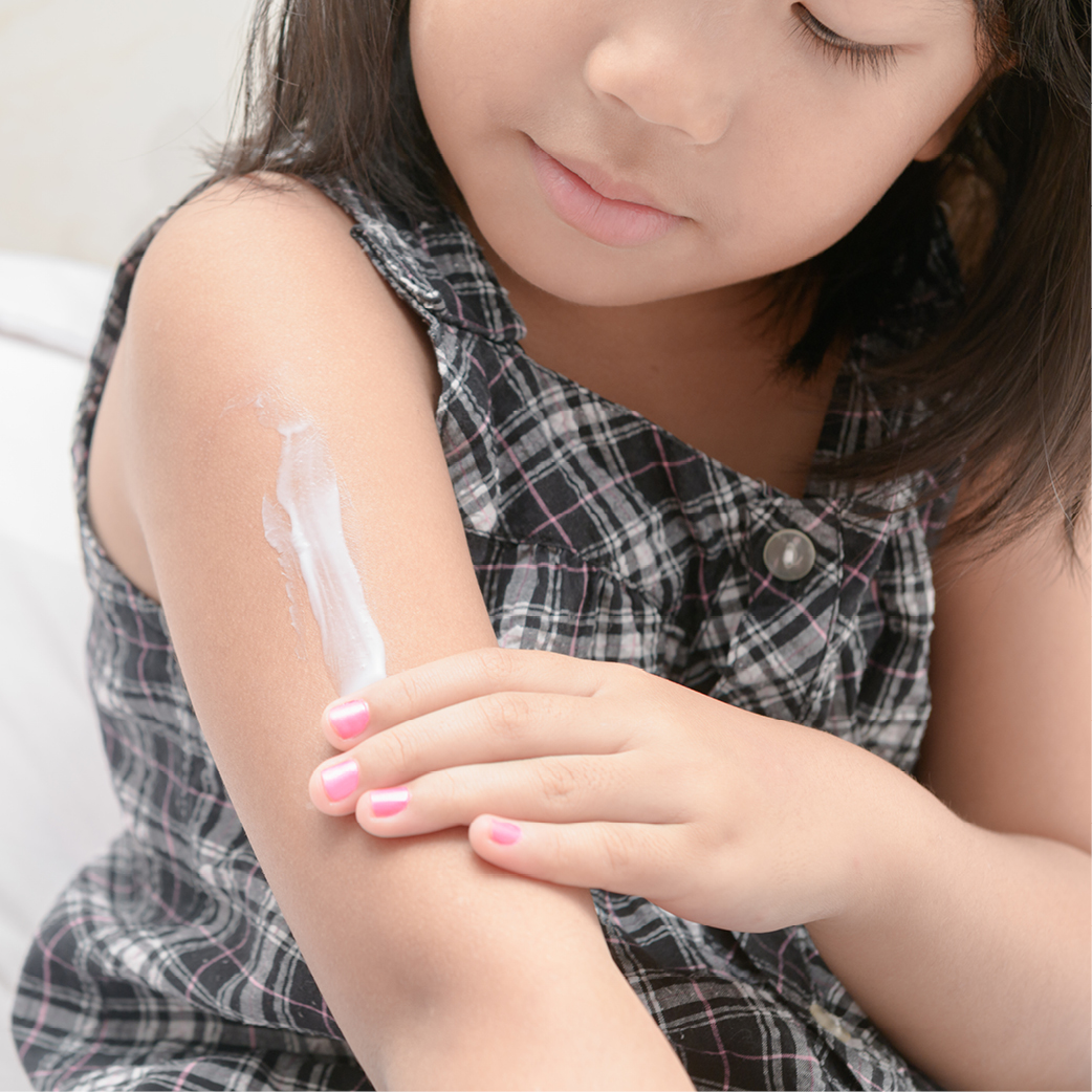 Mädchen cremt ihren Oberarm ein