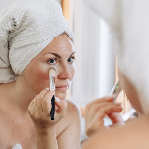 Eine Frau trägt Make-up auf ihre Teleangiektasien im Gesicht auf