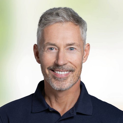 Lächelnder Mann mittleren Alter vor grünem Hintergrund