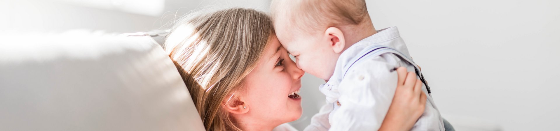 Mädchen sitzt mit Baby auf dem Sofa