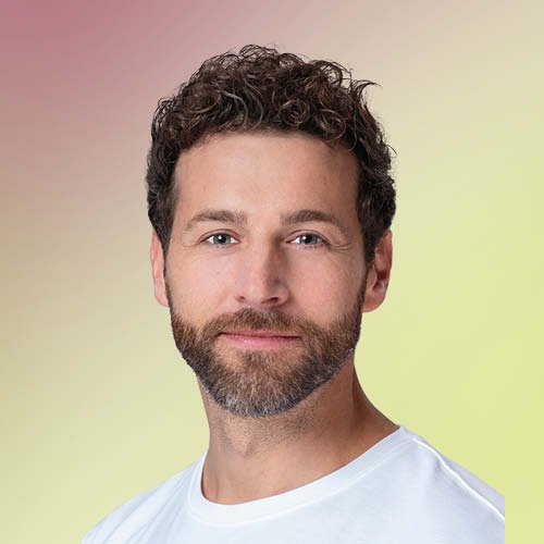 Freundlicher Mann mit braunem Haar vor rot-grünem Hintergrund