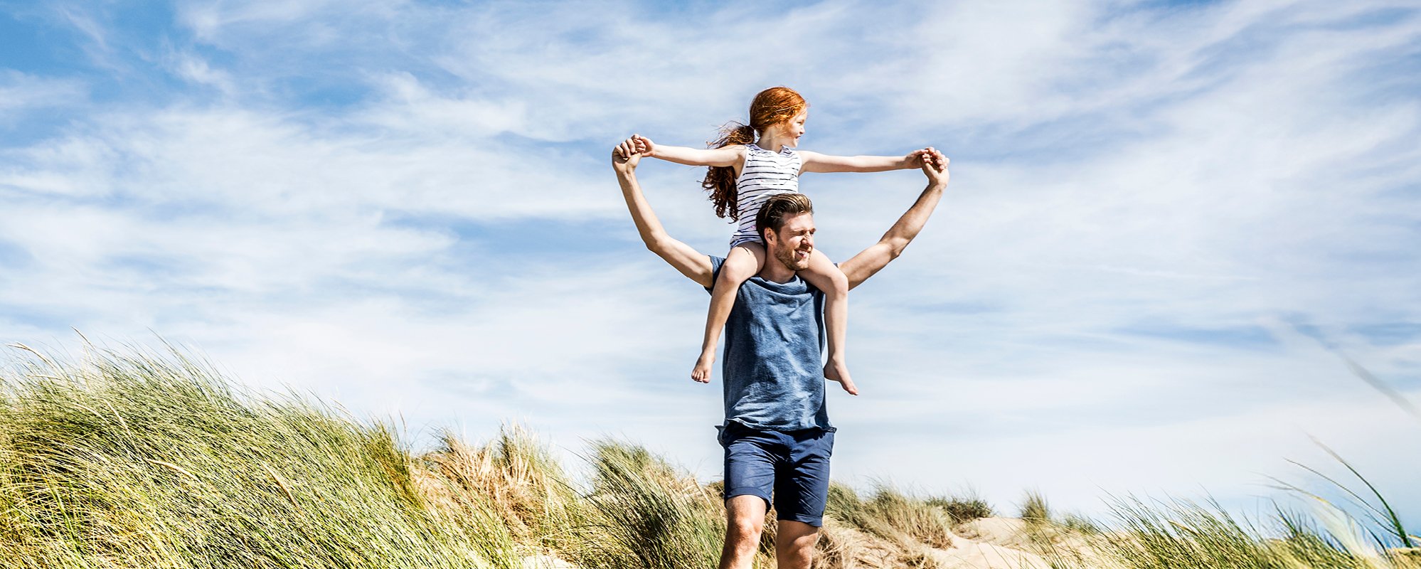 Sonnige Strandszene, Vater trägt seine Tochter auf den Schultern