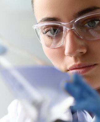 Nahaufnahme einer Laborantin, die eine Flüssigkeit betrachtet