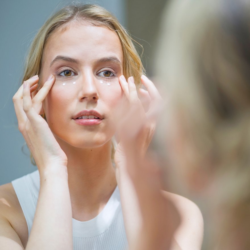 Frau trägt Augencreme auf