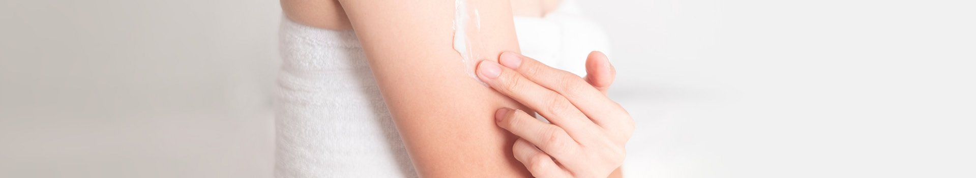 Eine Frau cremt sich mit After Sun-Pflege den Oberarm ein