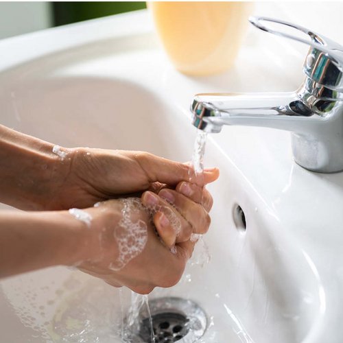 Hände werden unter einem Wasserhahn gewaschen.