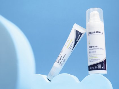 DERMASENCE Seborra Pickel-Akutroller und DERMASENCE Seborra Hautklärendes Serum vor blauem Hintergrund