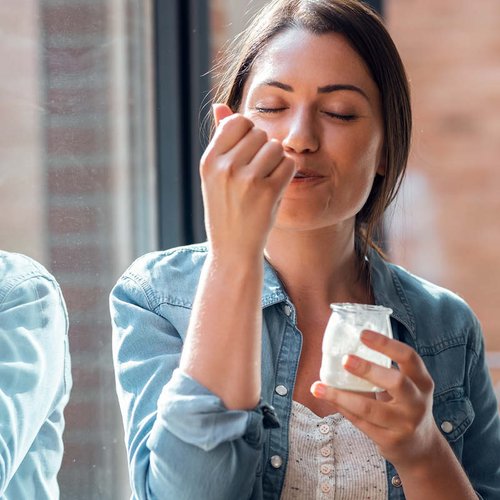 Eine Frau isst genüsslich ihren Joghurt.