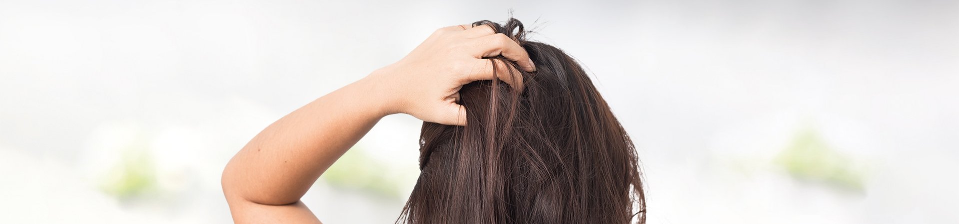 Brünette Frau kratzt sich an der Kopfhaut