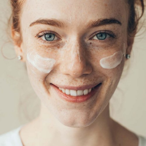 Rothaarige Frau mit Creme im Gesicht
