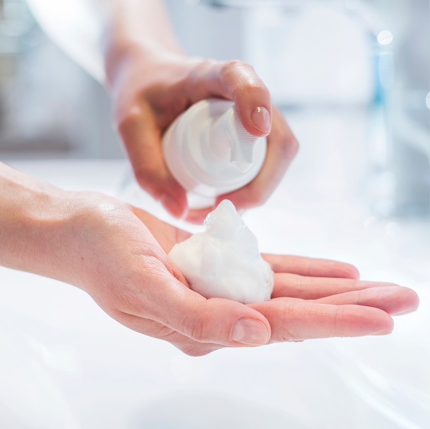 Hände, die einen Gesichtsreinigungsschaum auftragen