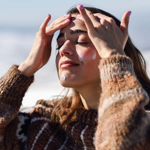 Brünette Frau mit Hut lacht in der Sonne