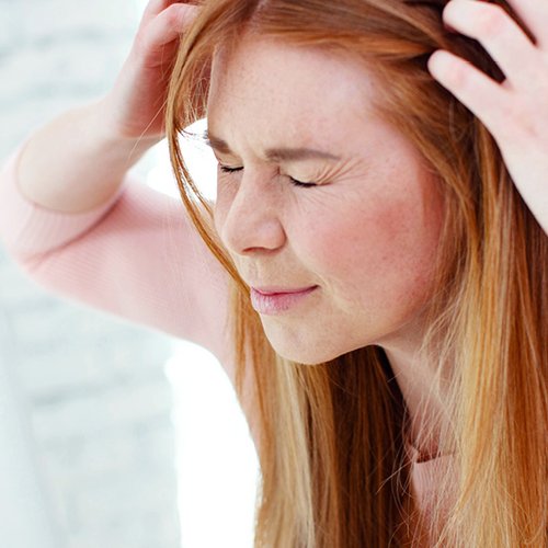 Frau leidet unter juckender Kopfhaut und kratzt sich