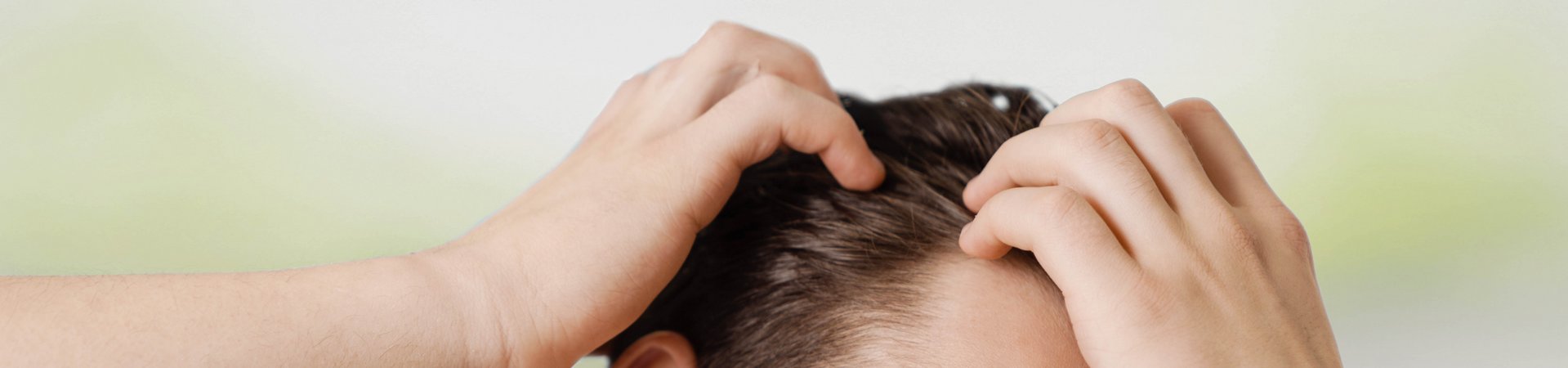 Dunkelhaariger Mann fährt sich mit Händen durchs Haar