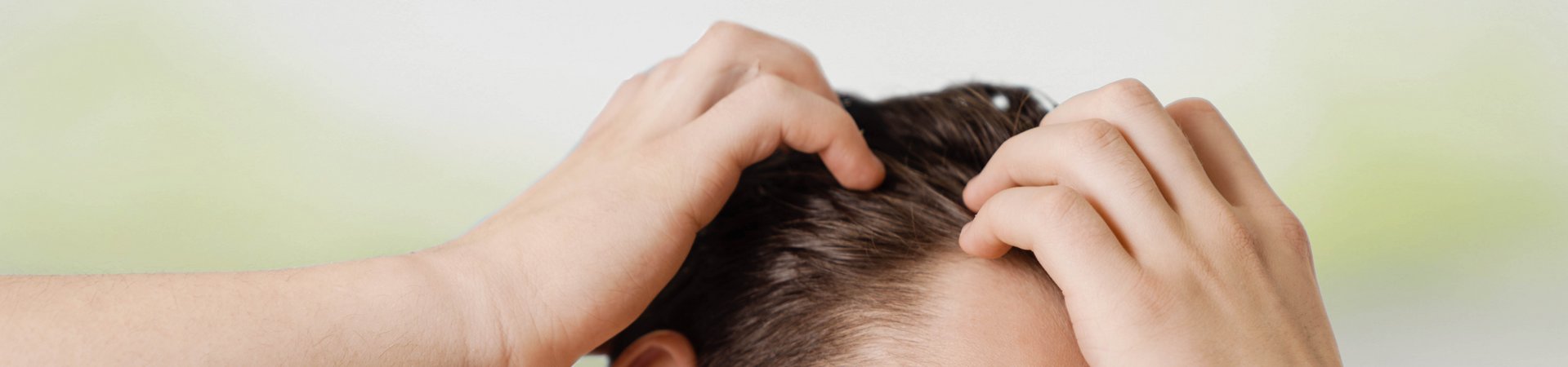 Dunkelhaariger Mann fährt sich mit Händen durchs Haar