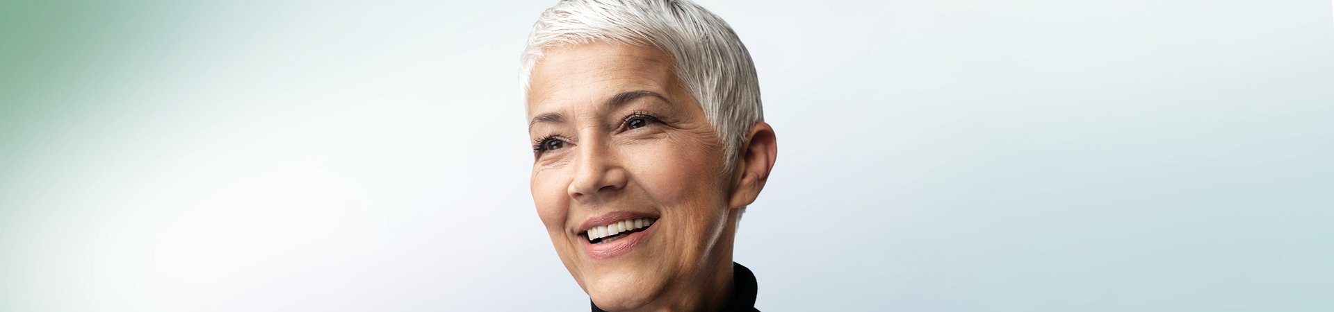 Lächelnde Frau mit kurzen Haaren vor hellblauem Hintergrund