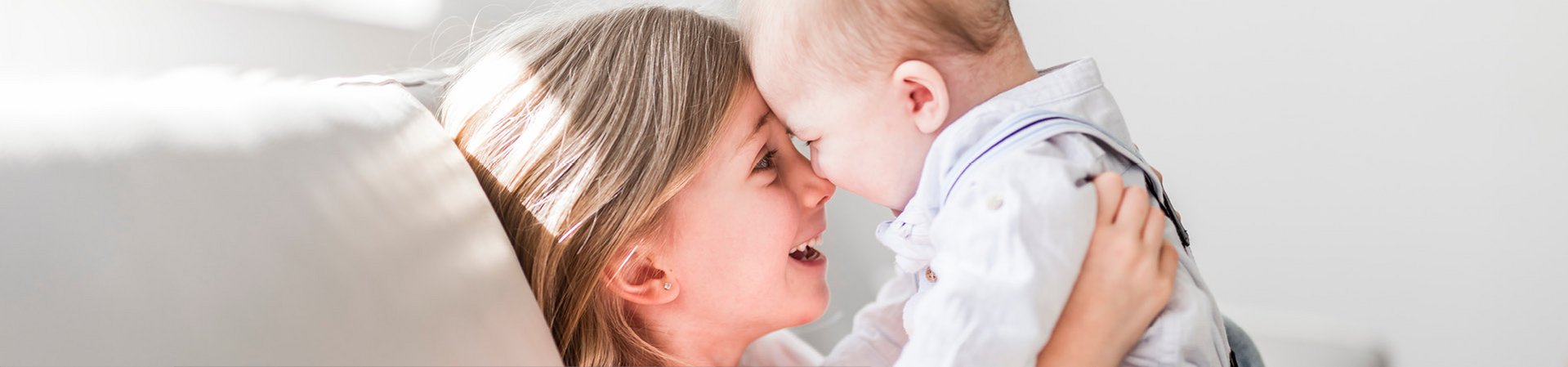 DERMASENCE bietet die passende Pflege für Kinderhaut Die große Schwester spielt mit ihrem Babybruder auf dem Sofa