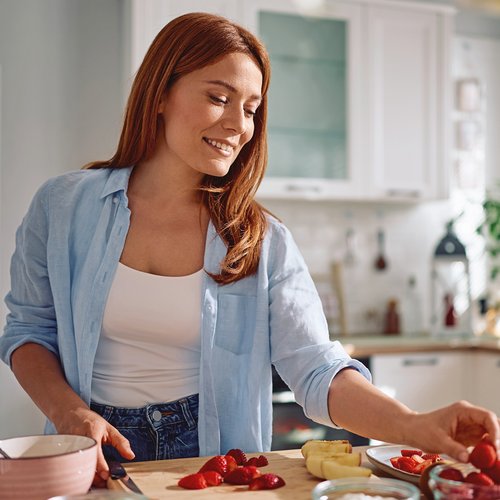 Frau schneidet Obst in der Küche