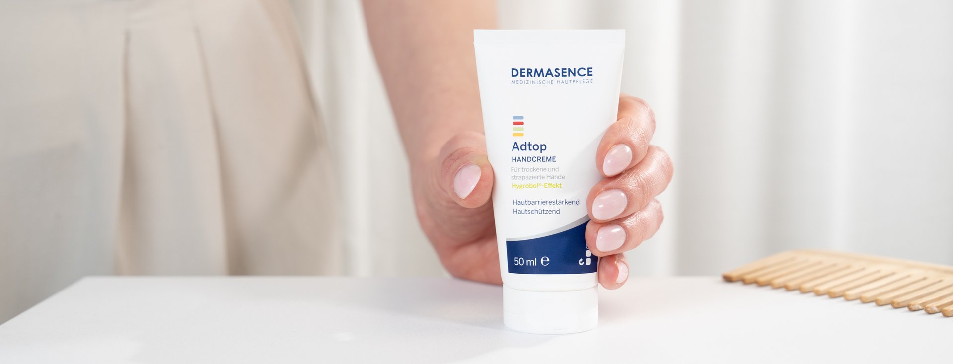 Hand hält eine Tube der DERMASENCE Adtop Handcreme