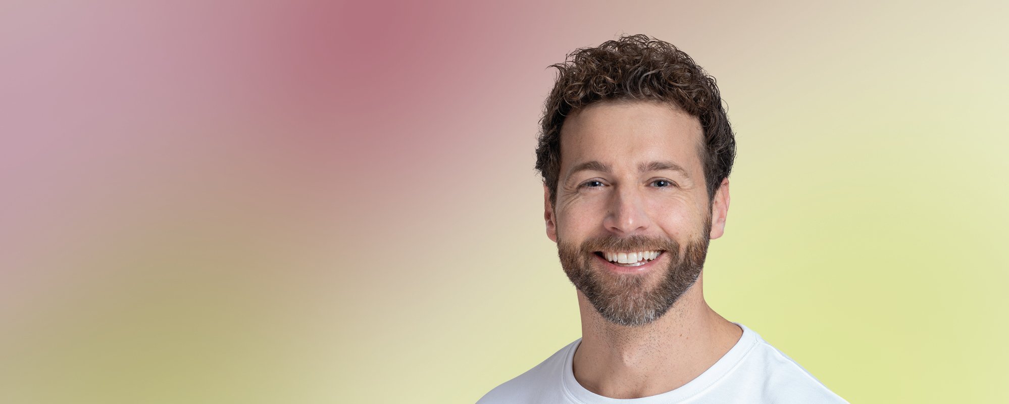 Gesicht eines bärtigen Mannes mittleren Alters, der zuversichtlich guckt.